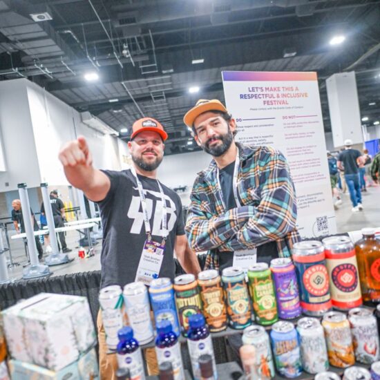 Two men stand behind a beer sampling table