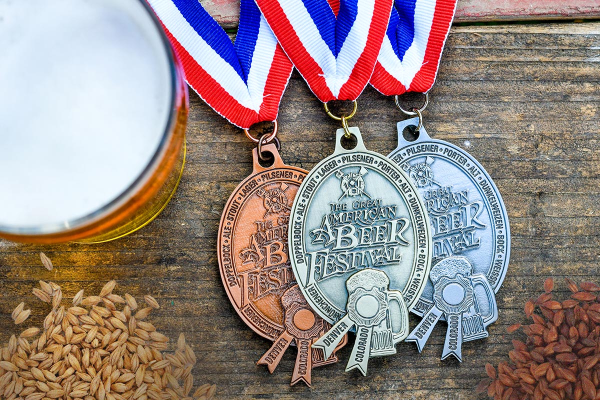 Great American Beer Festival medals next to a glass of beer and malt