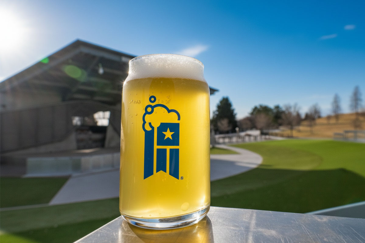 A glass of beer with an outdoor amphitheater in the background